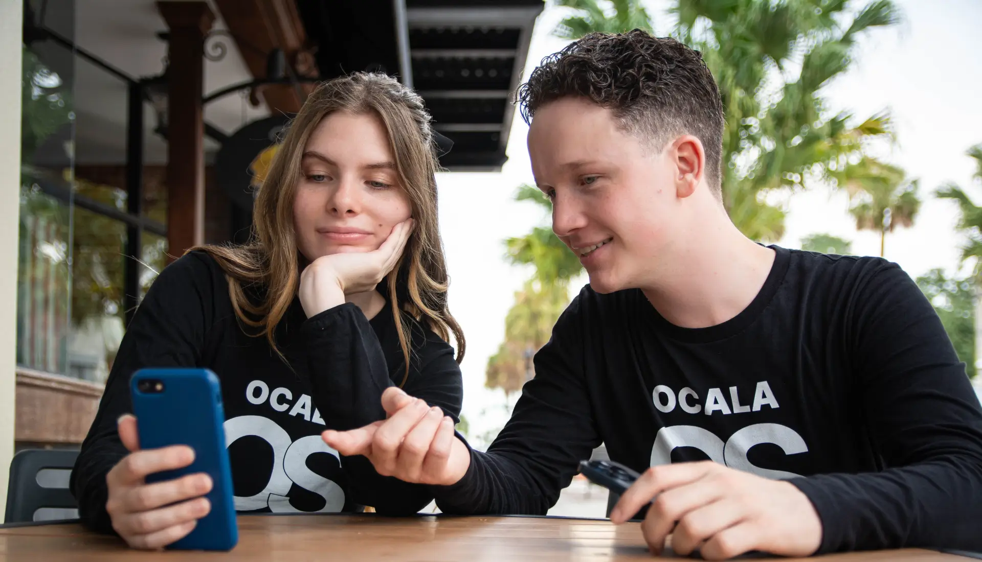 Brenden and Caidance from Ocala Social check out a social media post on an iphone